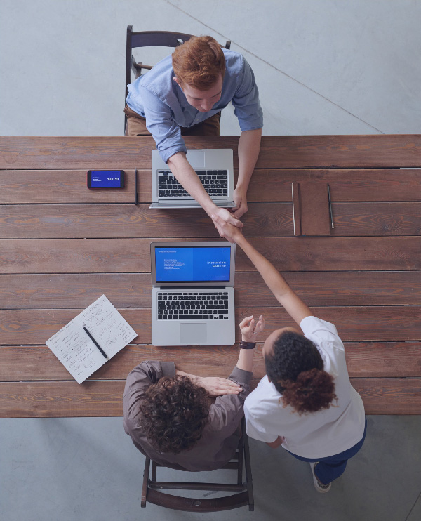 Overhead view of people shaking hands across a table.